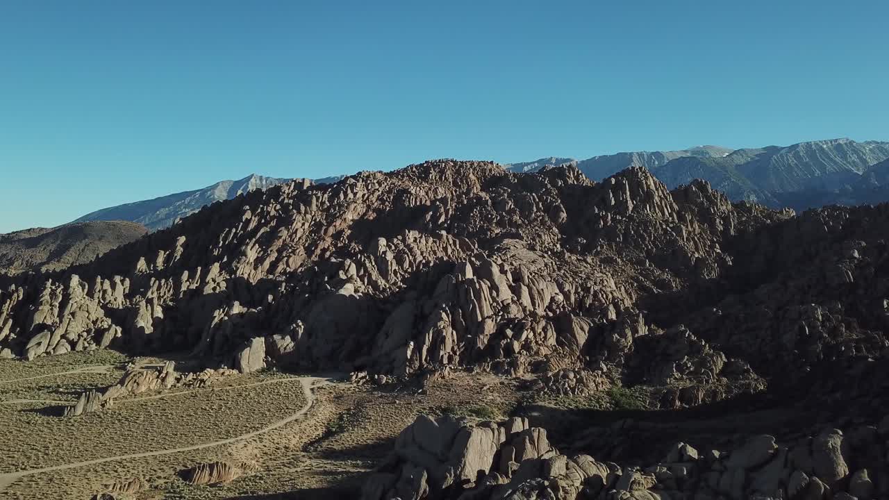 Alabama Hills, Slope of Sierra Nevada, California USA. Cinematic Drone Aerial View on Rock Formations Under Summer Sun and Clear Sky