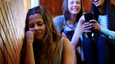 school friends bullying a sad girl in school corridor
