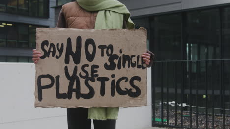 Joven-Activista-Climática-Estadounidense-Con-Pancarta-Protestando-Contra-Los-Plásticos-De-Un-Solo-Uso-Mientras-Mira-La-Cámara