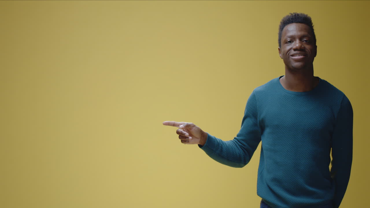 A man pointing his finger to the left on a yellow background