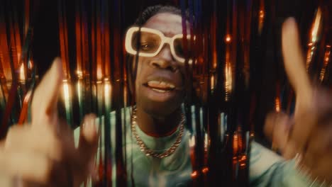 black hip-hop artist rapping to camera behind tinsel curtains in nightclub