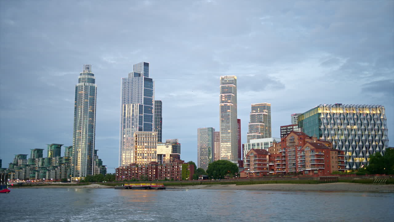 View of London from a floating boat on the Thames River at sunset, United Kingdom. Skyscrapers and modern buildings located along the river