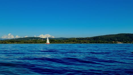 low-angle pov of small boat sailing in calm open lake waters of maggiore lake in italy