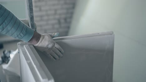 repair worker in white gloves holds large measuring ruler