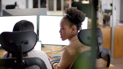 young african american woman and biracial woman collaborate in a business office setting