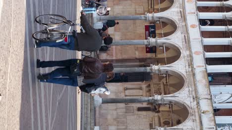 people walking and bicycling in a historic italian city square