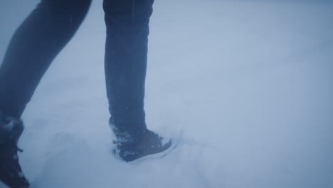 Hiker-walk-in-deep-fresh-snow-during-snowfall,-feet-close-up