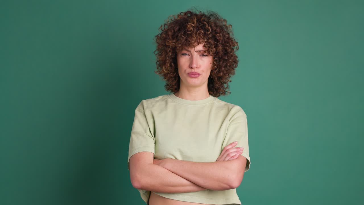 Disagreeing young woman shaking head with twisted mouth on green background