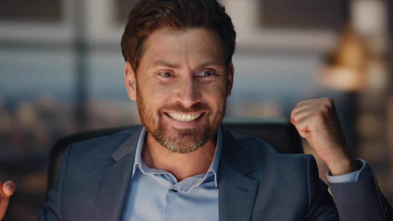 un hombre de negocios feliz celebrando el éxito en la oficina nocturna.