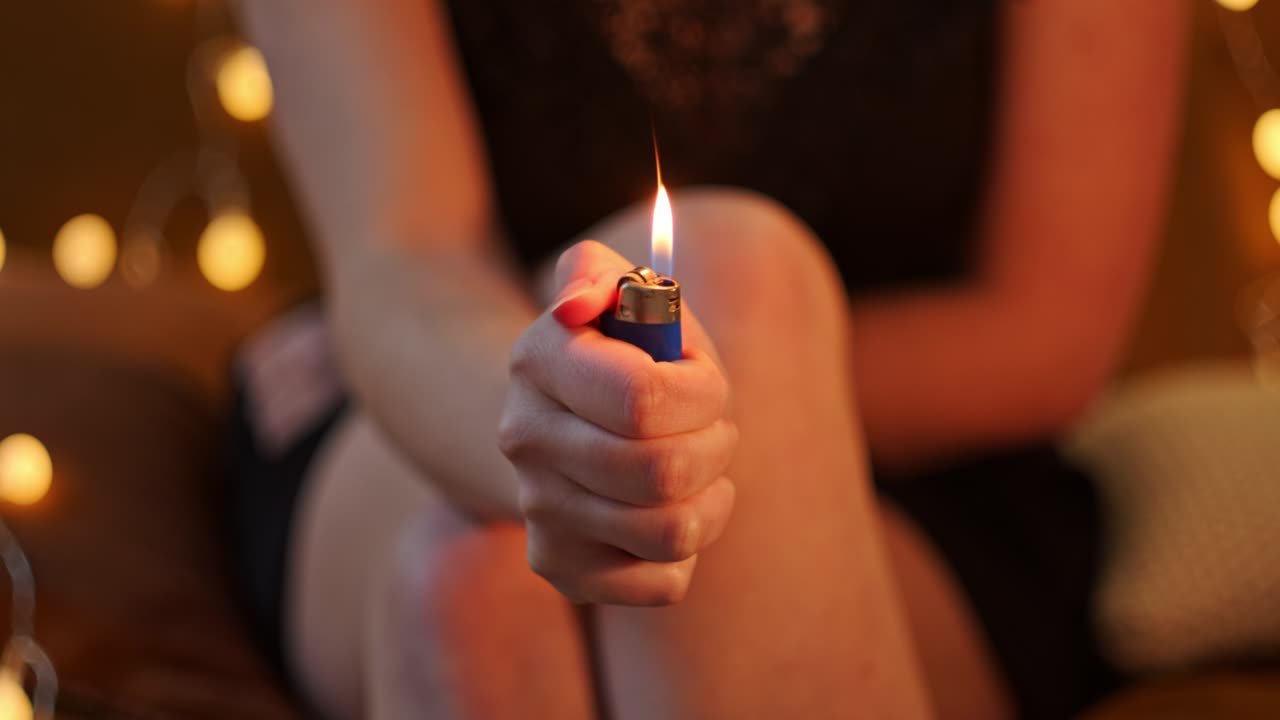 retrato recortado de una mujer sentada, sosteniendo y encendiendo un encendedor. primer plano, enfoque selectivo