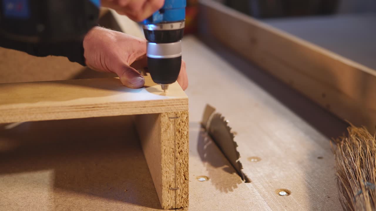 vista de cerca del proceso de carpintería. ensamblaje de componentes de madera utilizando un taladro eléctrico.