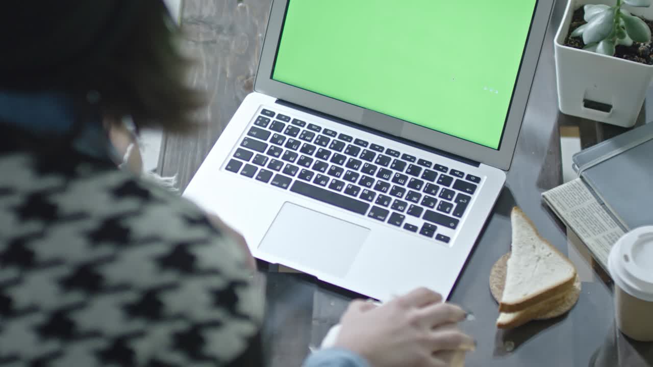 mujer escribiendo en una computadora portátil con pantalla verde