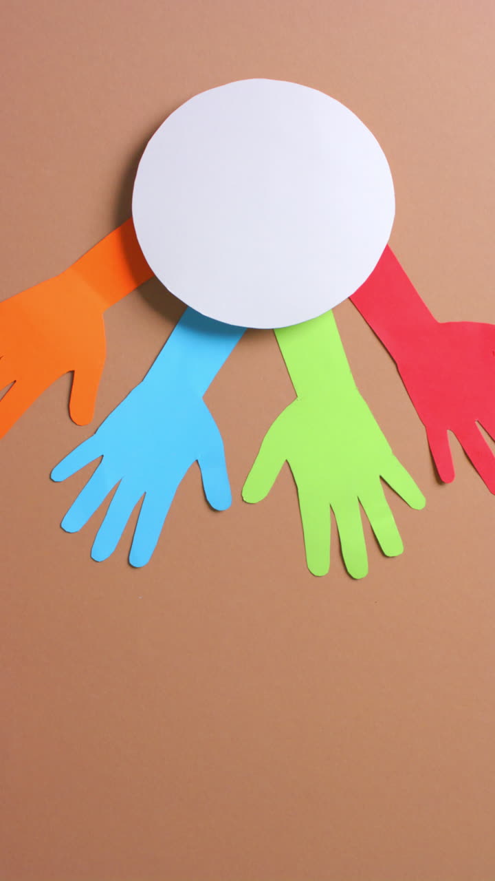 Vertical video of hands around circle made of colourful paper on brown background with copy space