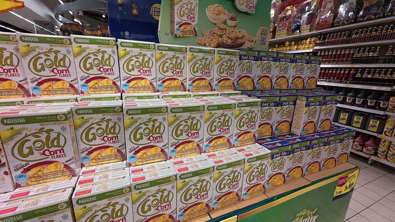 Commercially packaged cornflakes are displayed for sale in a large supermarket. They are organized by various brands and sizes, ensuring neat categorization for shoppers.