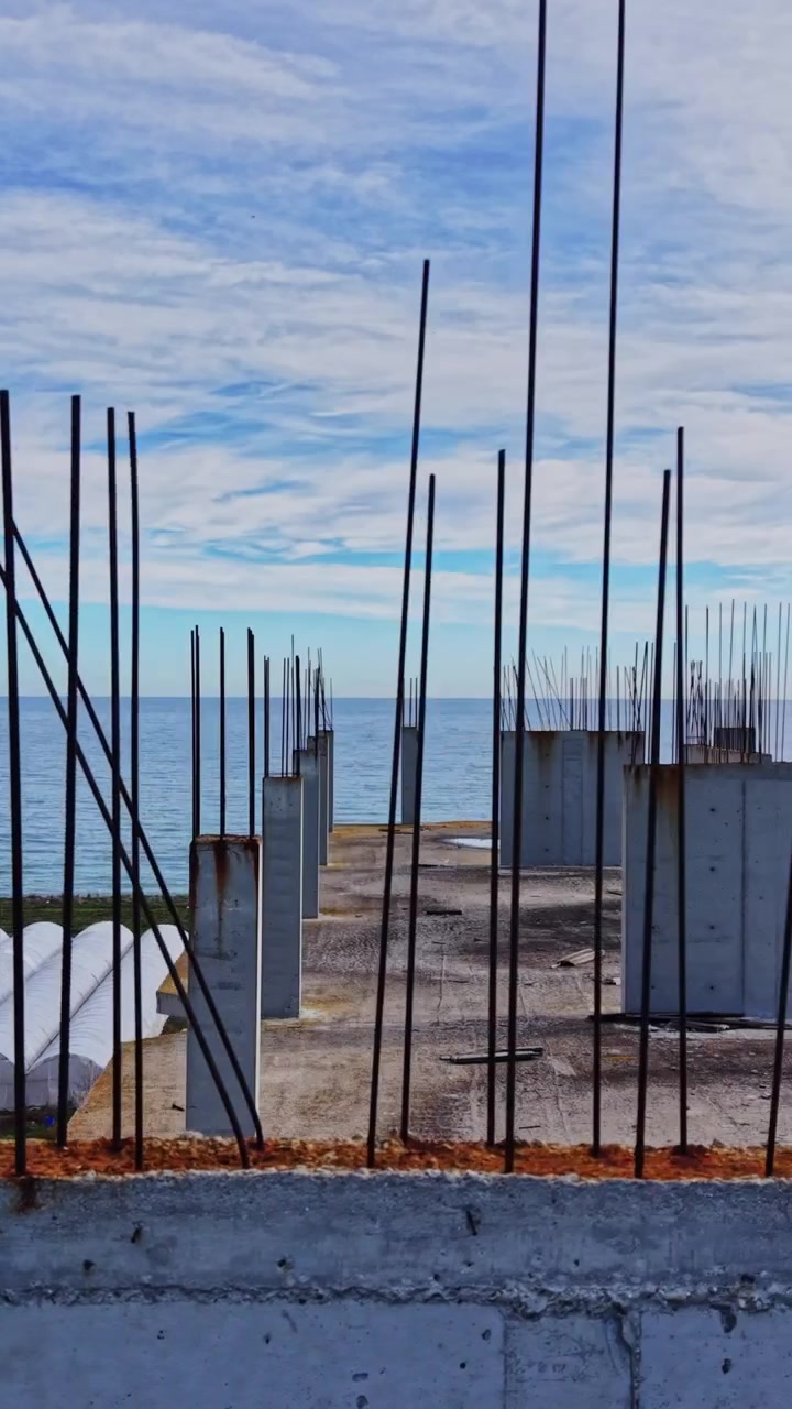 Construction site overlooking the ocean with rebar and cloudy sky