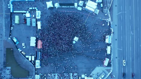 mosh-pit-fans-gather-to-watch-stage-performance-surrounded-by-food-trucks-mass-line-ups-with-a-big-screen-tv-as-white-beach-ball-gets-tossed-around-in-a-downtown-city-birds-eye-top-view-next-to-road