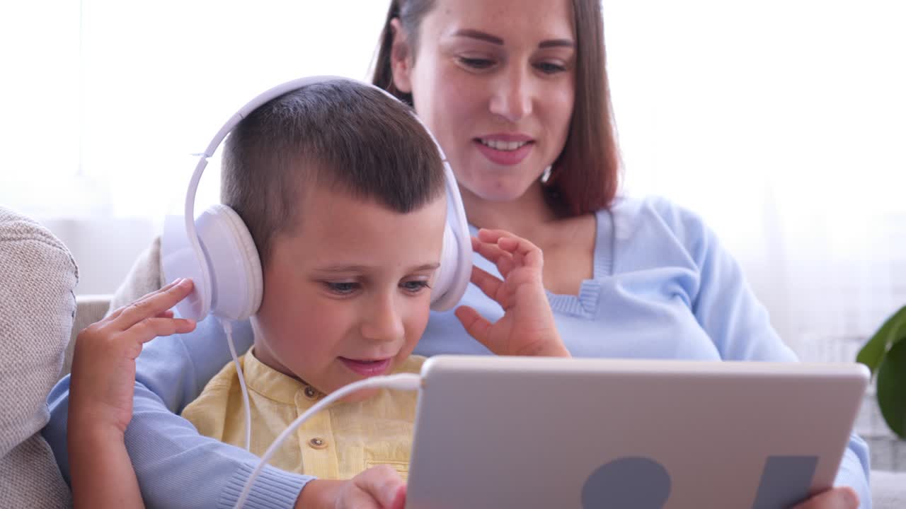 madre y hijo en auriculares viendo algo en la tableta