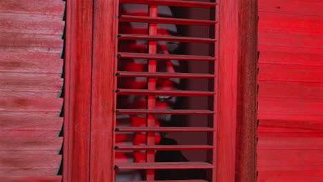 un hombre preocupado mira por la ventana de la persiana mientras la policía responde a una escena del crimen.