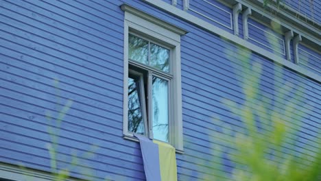 worn yellow and blue ukrainian flag displayed on window of house in latvia