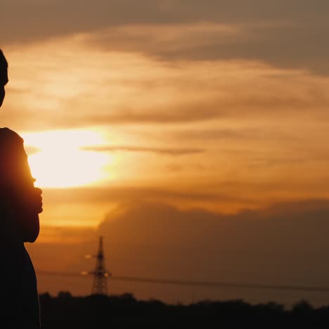 Die-Einsame-Silhouette-Einer-Frau-Bei-Sonnenuntergang,-Die-In-Die-Ferne-Starrt