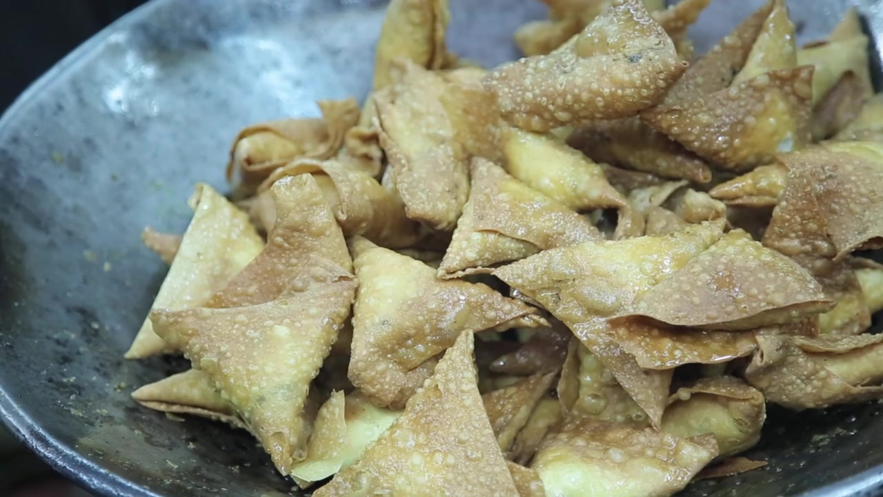 Samosa dorati e croccanti che vengono scolati dall'olio presso una bancarella di street food a Shivajinagar, Bangalore