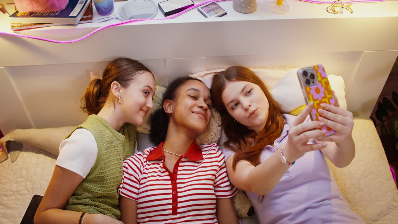 십대 소녀들이 침대에 셀피를 찍고 있다