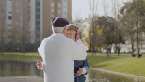 happy senior woman meeting and hugging her husband while standing at pier in city park