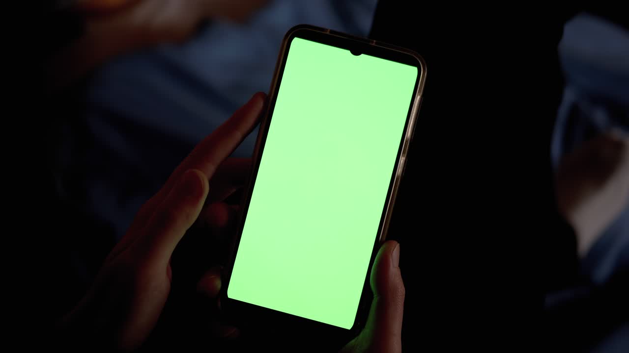 암흑의 여성 손은 녹색 터치 스크린으로 스마트폰을 들고 조사합니다.