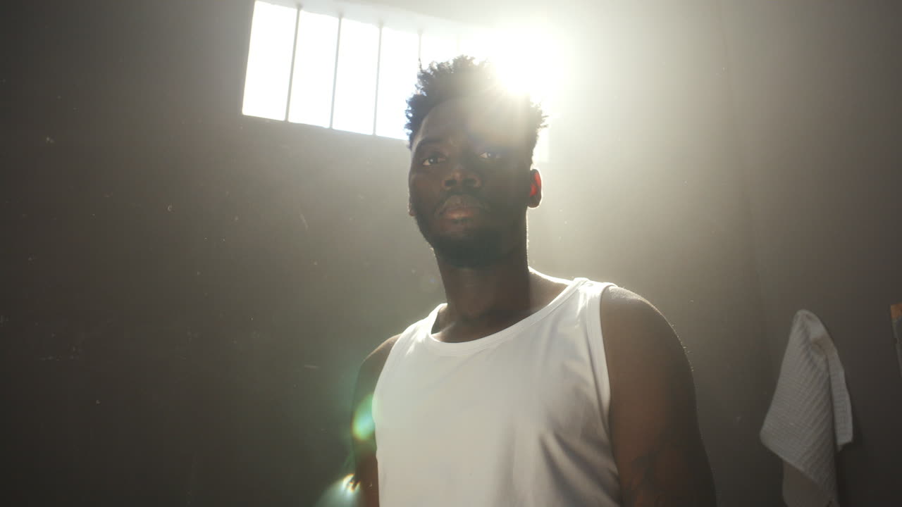 Portrait of Black Inmate Standing in Beam of Sunlight from Prison Window