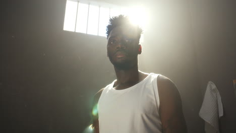 portrait of black inmate standing in beam of sunlight from prison window