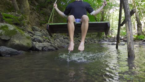 swinging on a swing over the stream. slow motion.