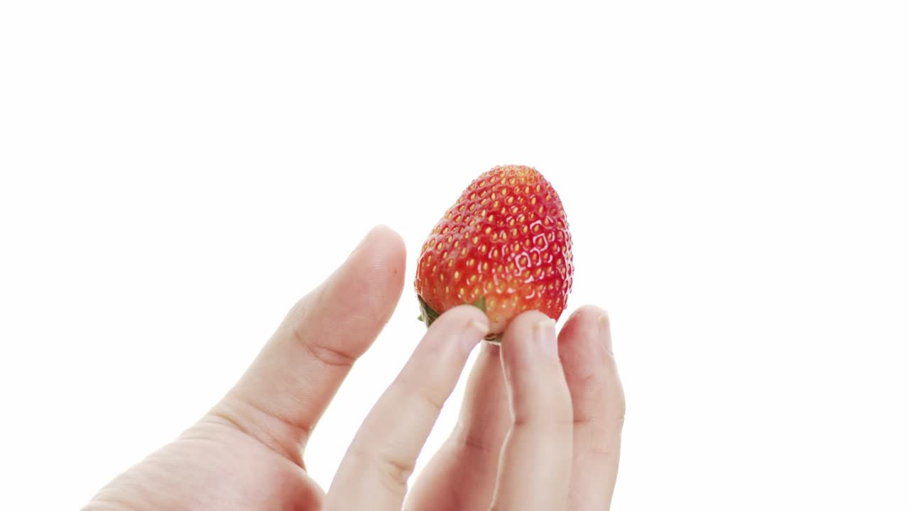 vista delantera sosteniendo fresas con los dedos girando lentamente.
