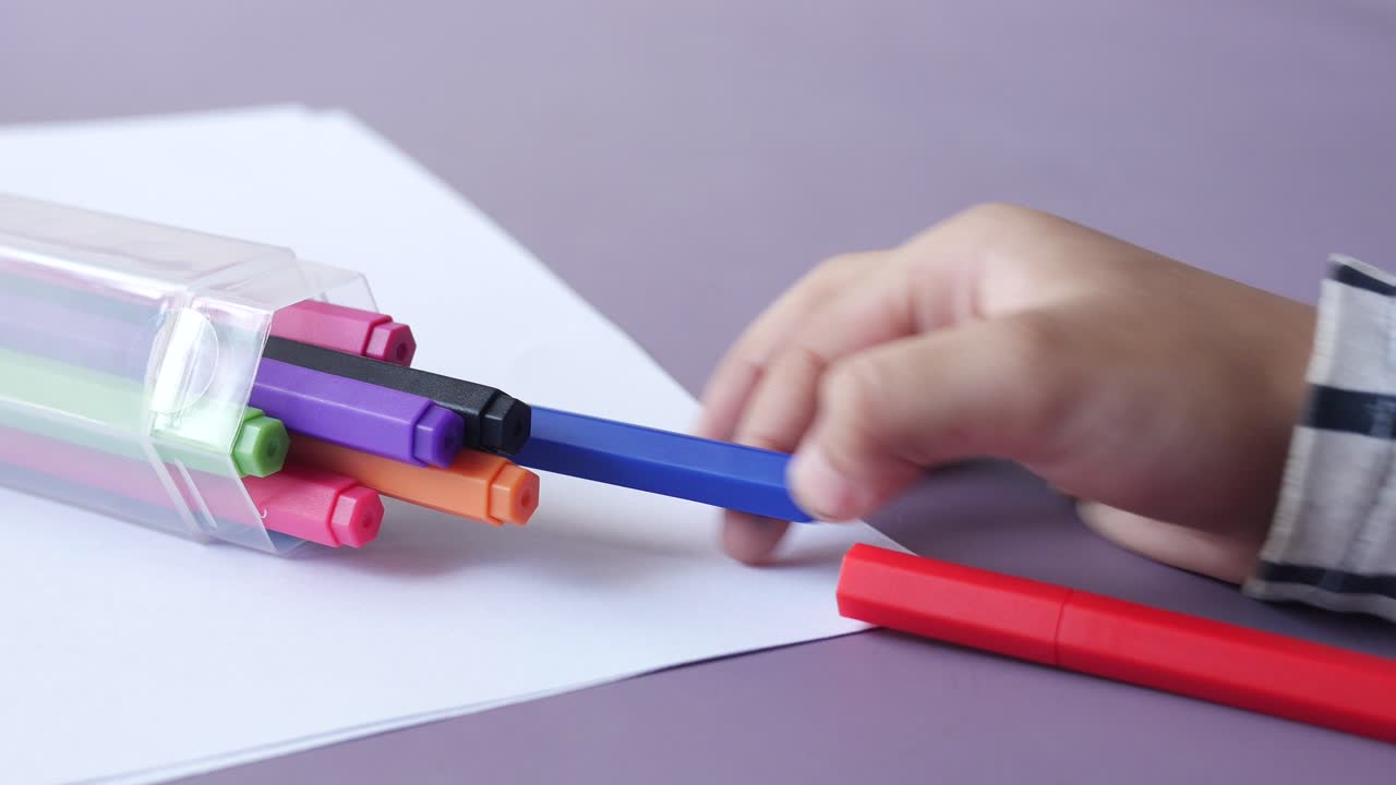 la mano de la niña recoge un lápiz