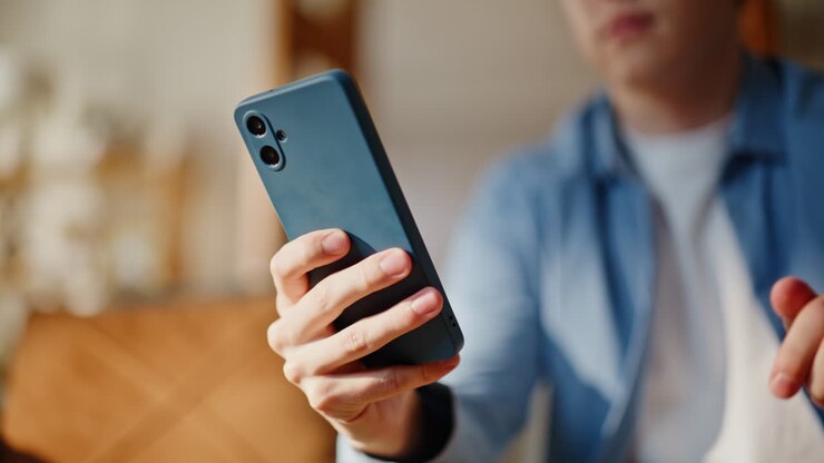 Primo piano di un uomo che manda messaggi con lo smartphone, rilassandosi sul divano di casa. Ragazzo che scrive un messaggio