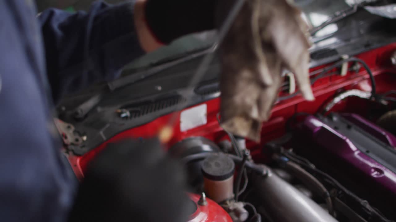 sección media del equipo de limpieza mecánica femenina del coche con un paño en una estación de servicio de coches