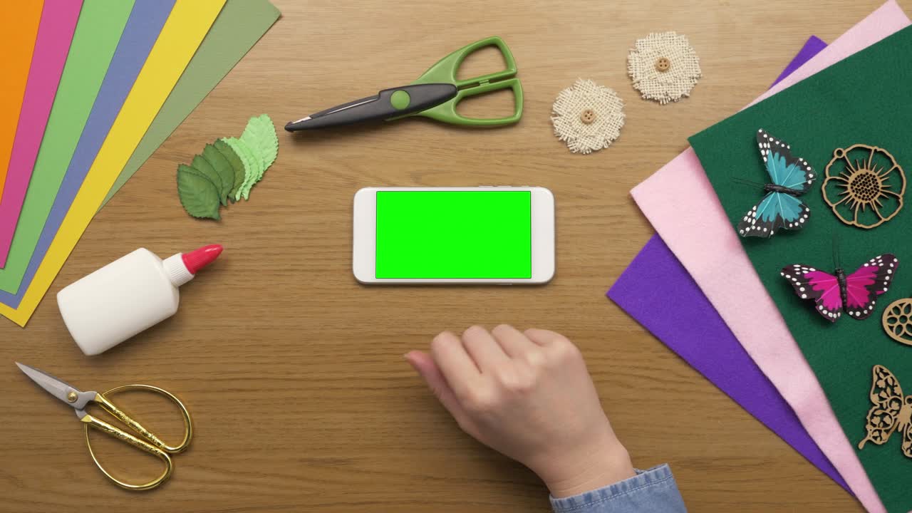 aérea de una mujer con teléfono inteligente y equipos de artesanía