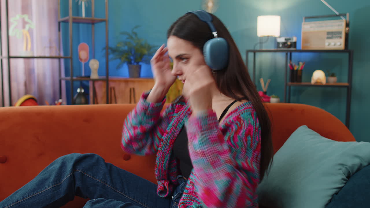 Happy woman in wireless headphones relaxing sleeping lying on sofa at home listening favorite music