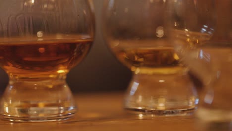 close-up of whiskey glasses swirling on wooden bar with warm lighting and relaxed atmosphere