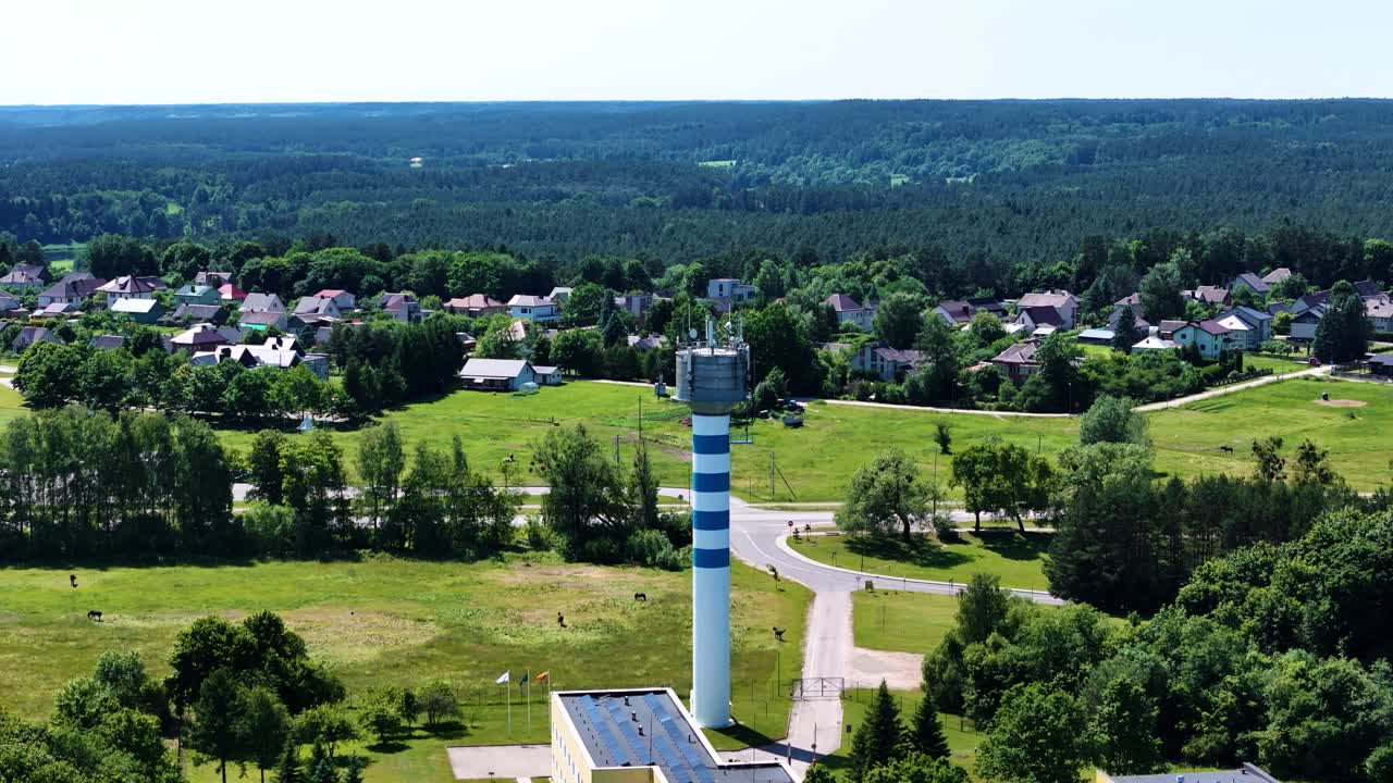 Blue and white color water tower near Birstonas in Lithuania, aerial orbit view