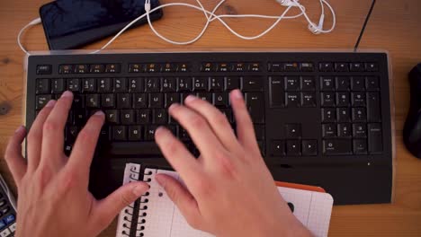 young man is writting a text on his computer using a keyboard