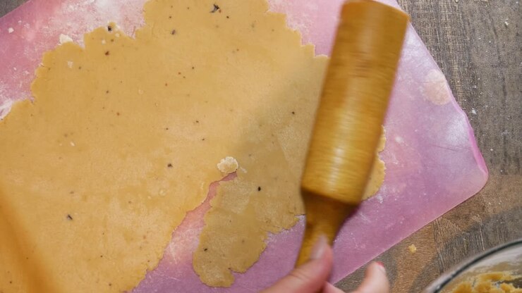 Female hands are using a wooden rolling pin for gingerbread cookie dough