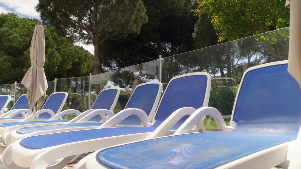 Close view along rows of blue sun loungers beside a transparent glass safety barrier