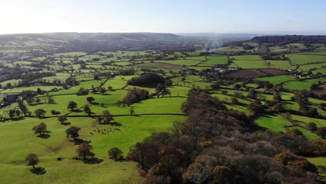 aerial backwards shot looking over green fields and the east devon countryside england uk