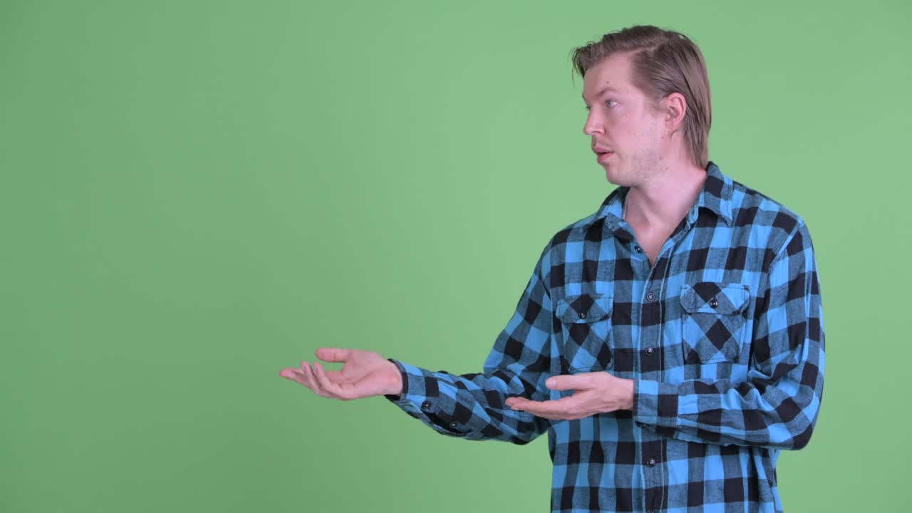 Portrait of Caucasian man looking sad and giving thumb down shot against green studio background