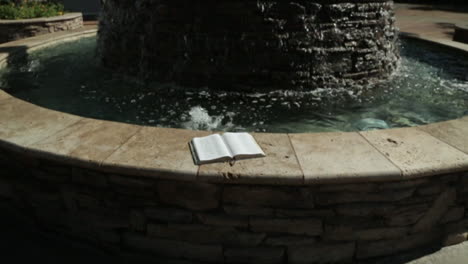 holy book by a peaceful water fountain background in slow motion