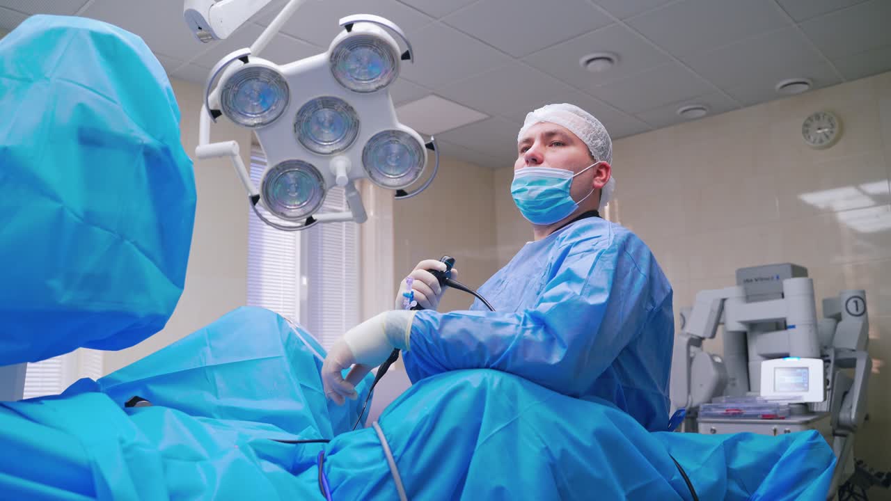 Surgery process. Professional doctor with nurse perform endoscopic operation to a patient. Operating room in modern clinic.