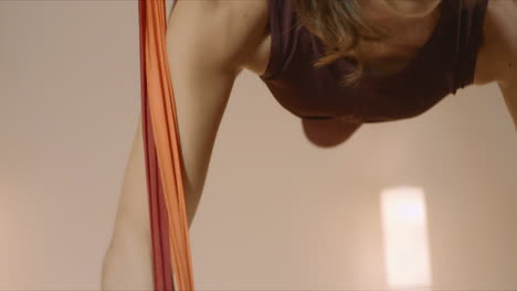 sports woman hanging upside down in hammock. girl practicing fly yoga in studio