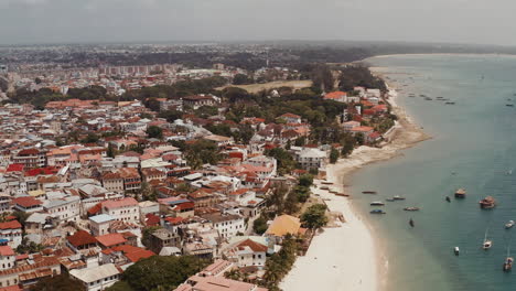 Blick-Auf-Die-Küstenlinie-Von-Sansibars-Steinstadt-Mit-Fischerbooten,-Die-An-Einem-Strahlend-Sonnigen-Tag-In-Der-Nähe-Des-Strandes-Vor-Anker-Liegen