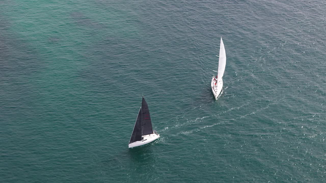 Two sailboats, one with white and one with black sail