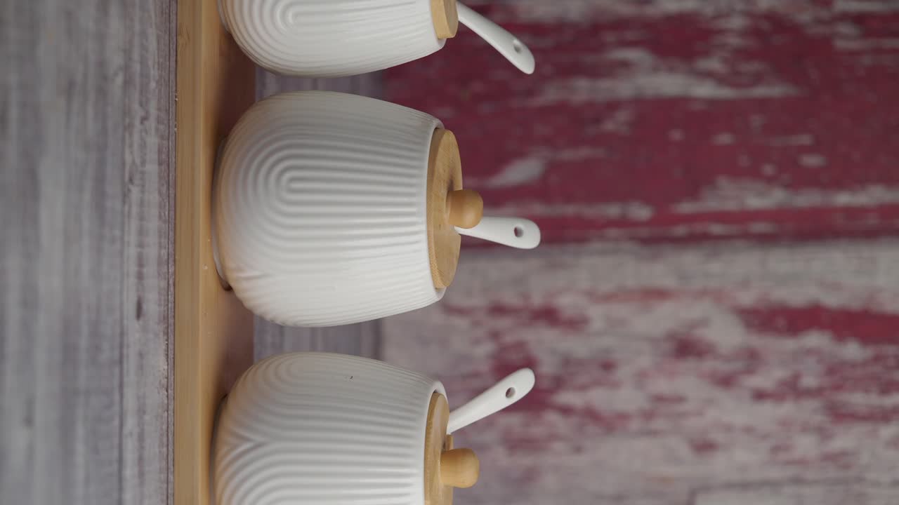 Three white ceramic spice jars on a wooden rack